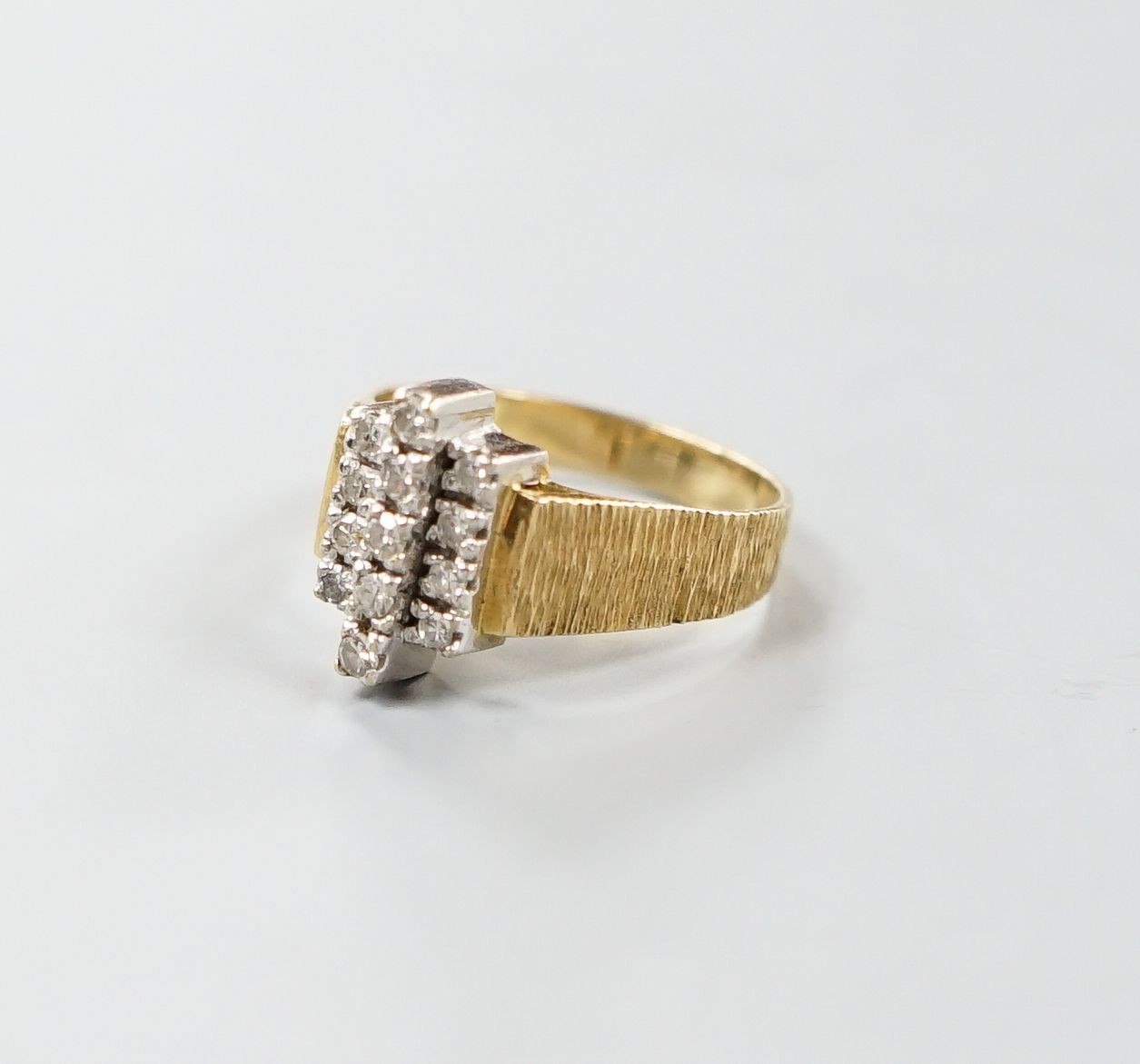 A 1970's textured 18ct gold and thirteen stone diamond set geometric dress ring, size Q, gross weight 5.3 grams.